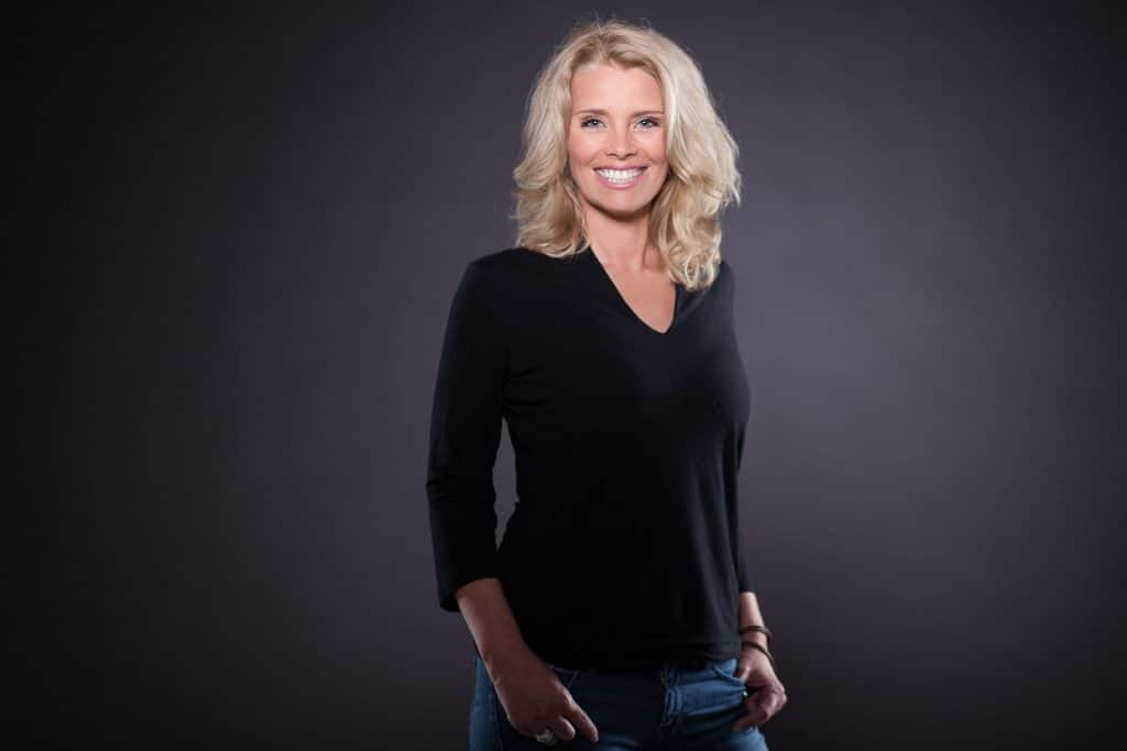 Portrait einer lächelnden blonden Frau im schwarzen Oberteil vor dunklem Studiohintergrund – Fotostudio Hamburg City Nord
